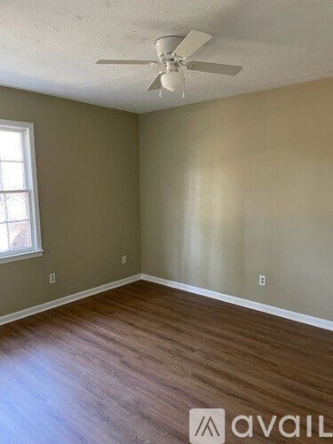 A room with a ceiling fan and wooden flooring.