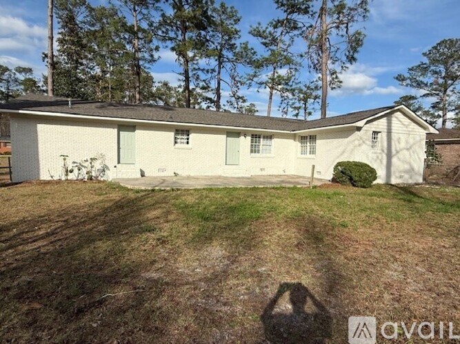 A white house with a brown roof and a green bush in front.