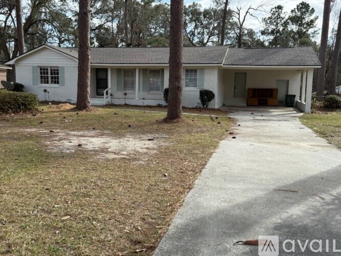 A house with a white exterior and a brown door is surrounded by trees.