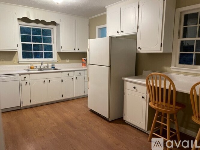 A kitchen with white cabinets and a wooden floor.