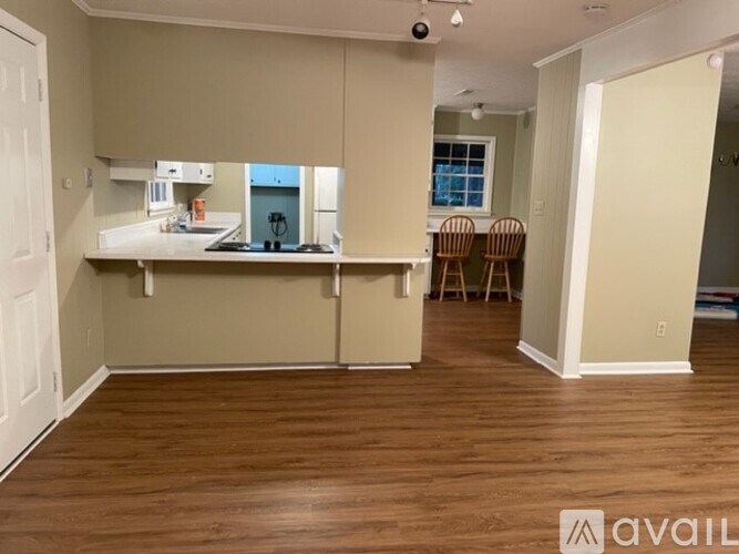 A room with wooden floors and a kitchenette area.