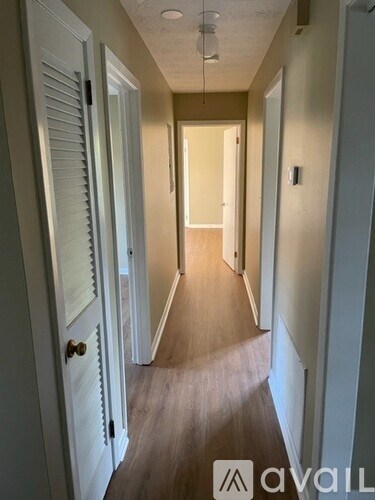 A long hallway with white doors on the left and a light on the wall on the right.