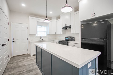 A kitchen with a white countertop and a black refrigerator.