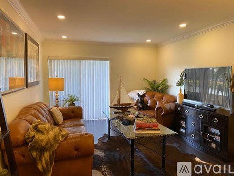 A living room with a brown leather couch and a glass coffee table.