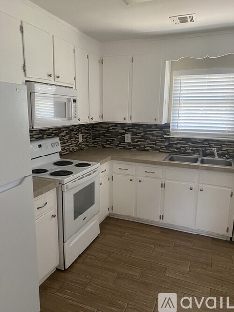 A kitchen with white cabinets and a stone backsplash.