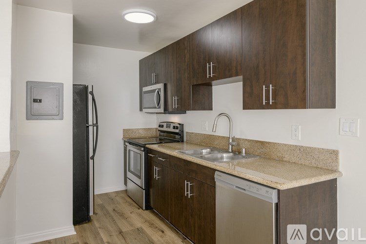 A kitchen with brown cabinets and a black refrigerator.