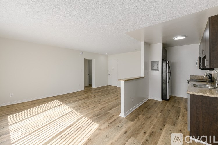A kitchen area with wooden flooring and white walls.