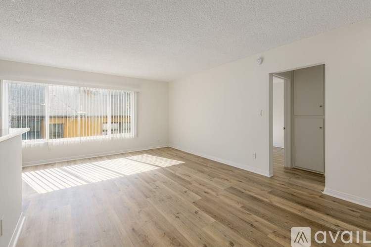 A room with wooden flooring and a door on the right side.