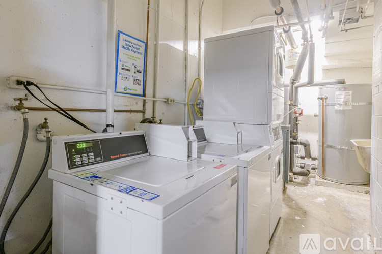 A machine with a digital display is in a room with industrial pipes.