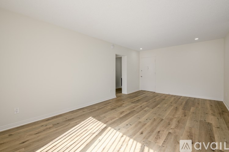 A spacious room with wooden flooring and white walls.