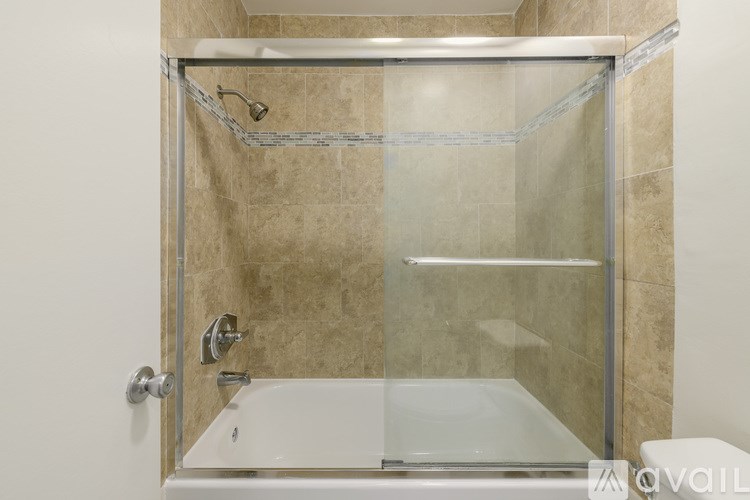 A shower area with a glass door and a glass shower head.