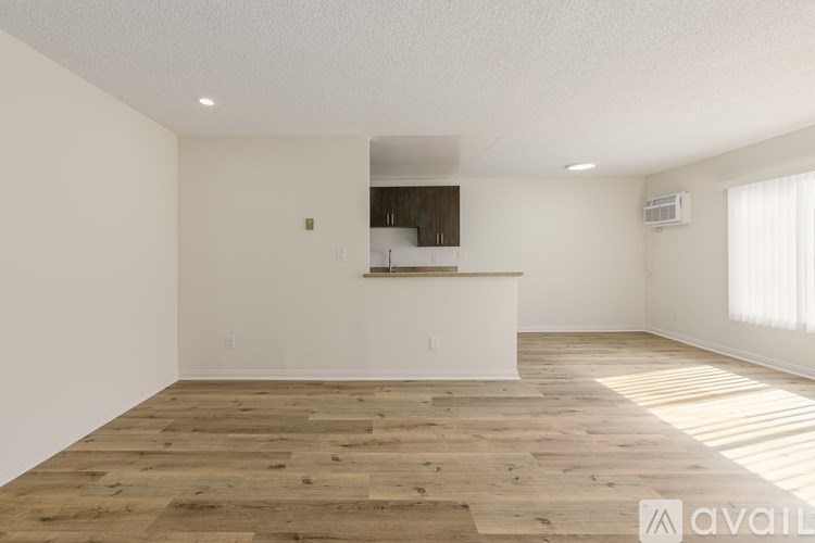 A spacious room with wooden flooring and a white wall.