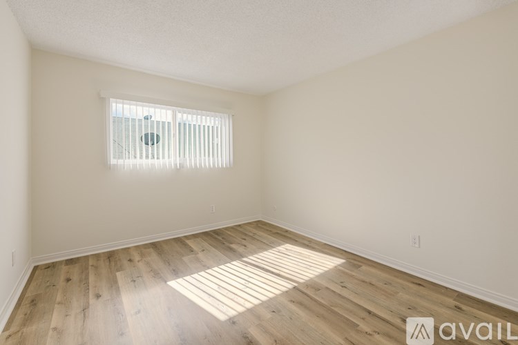 A room with wooden flooring and a window with blinds.