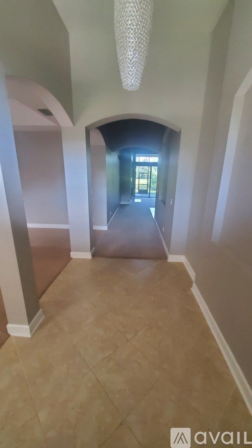 A hallway with a chandelier and arched doorways.