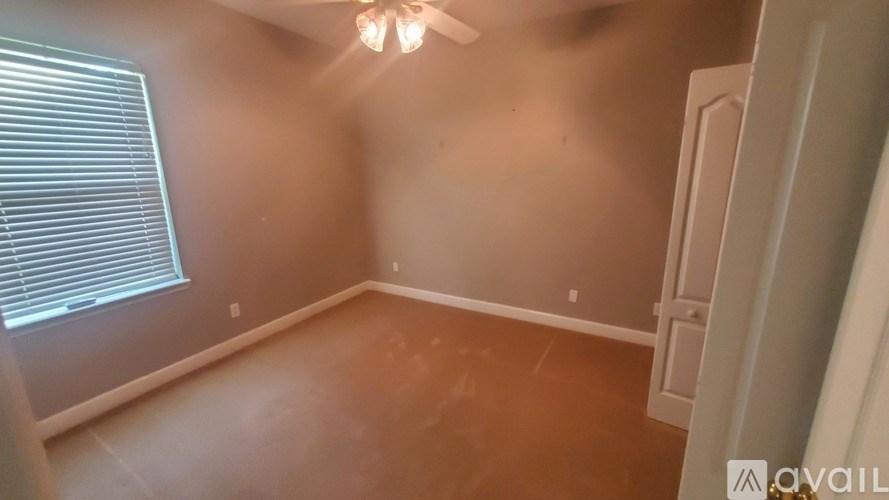 A room with a ceiling fan and a window with blinds.
