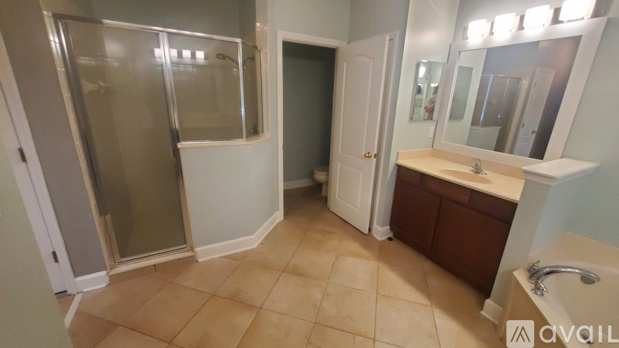 A bathroom with a glass shower door and a sink with a mirror above it.