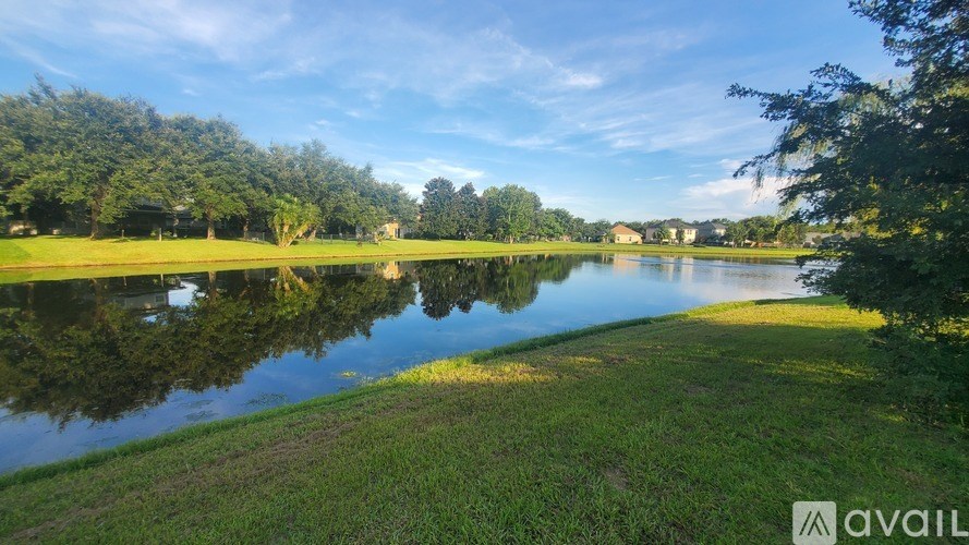 A serene landscape with a lake, trees, and a clear sky.