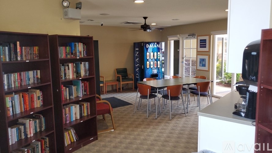 A room with a bookshelf, chairs, and a table.