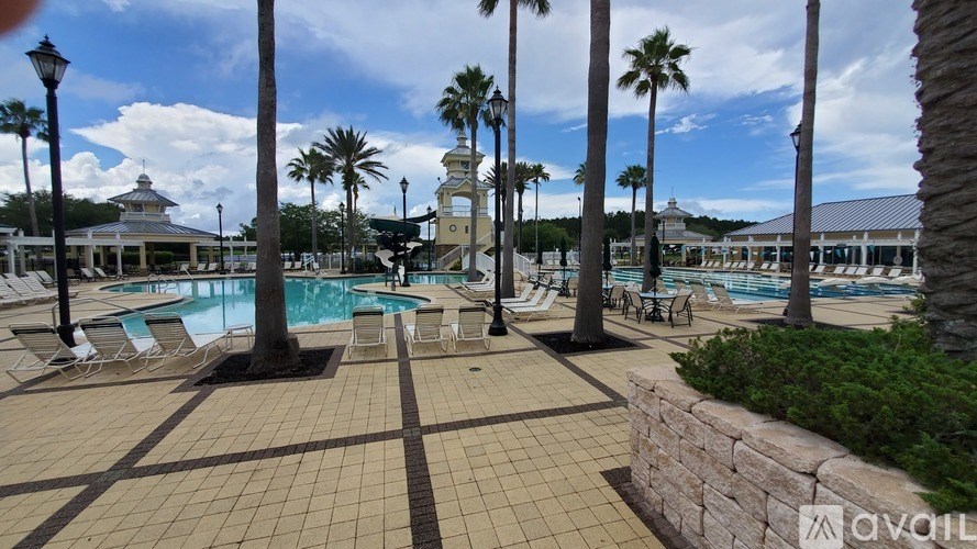 A pool area with palm trees and a stone wall.
