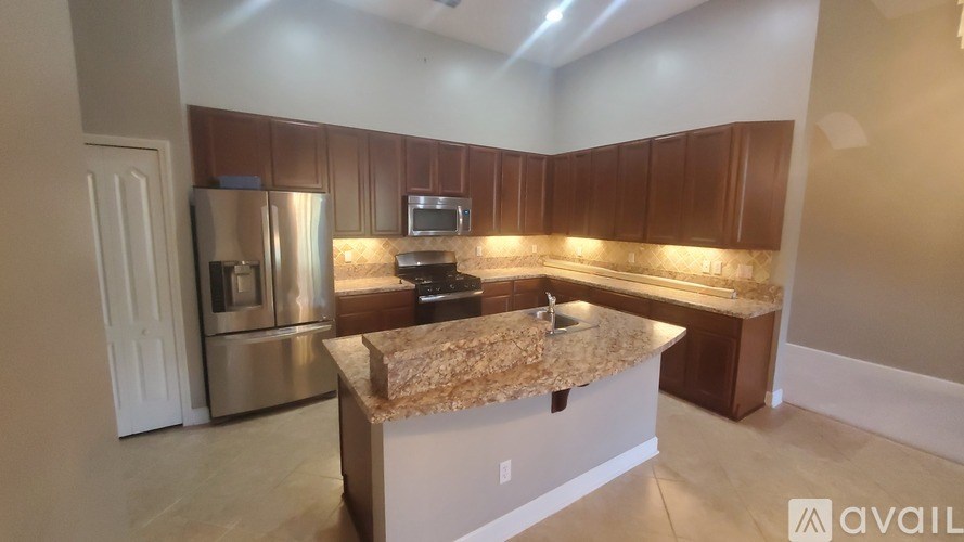 A kitchen with a granite countertop and stainless steel appliances is available for rent.