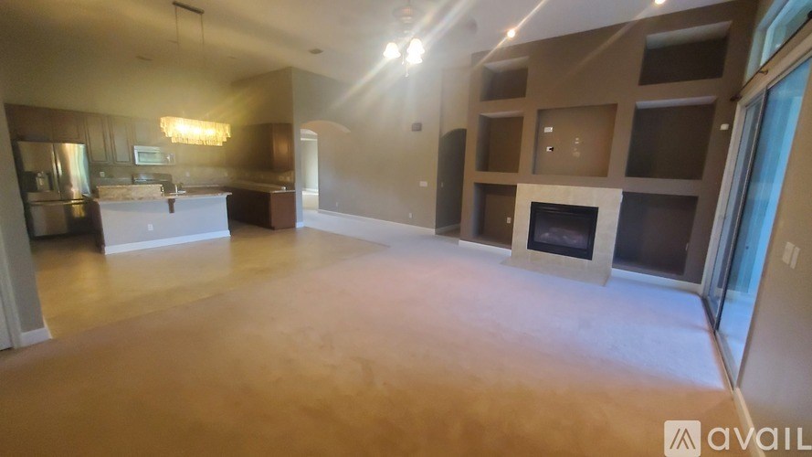 A spacious living room with a kitchen area in the background.