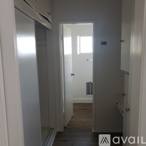 A hallway with a door on the right and a refrigerator on the left.