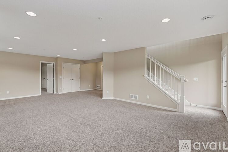 A spacious room with carpeted floor and a window on the right side.