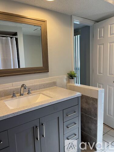 A bathroom with a sink, mirror, and grey cabinets.