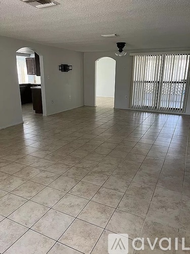 A spacious room with tiled flooring and a ceiling fan.