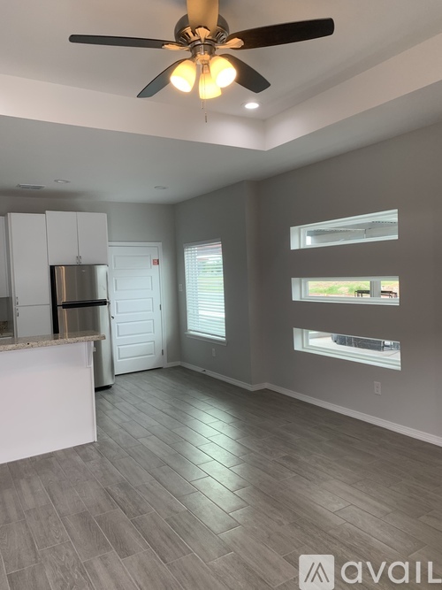A spacious kitchen and living room with a ceiling fan and lighting.