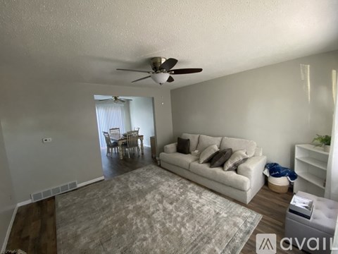 A living room with a couch, a dining table, and a ceiling fan.