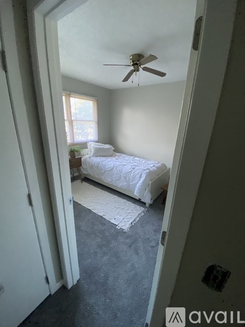 A bedroom with a bed, a ceiling fan, and a window.