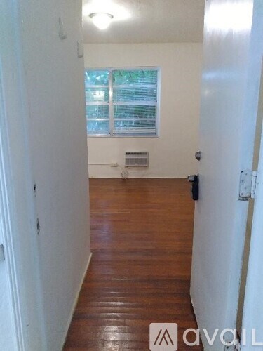 A hallway with wooden floors and white walls.