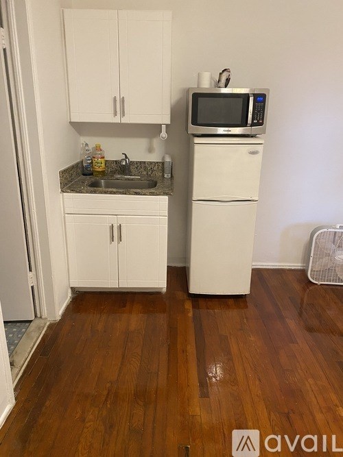 A kitchen with white cabinets and a wooden floor.