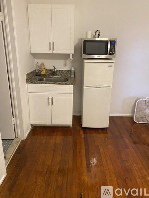 A kitchen with white cabinets and a wooden floor.