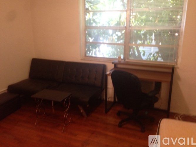 A black sofa with a black chair and a black office chair in front of a window.