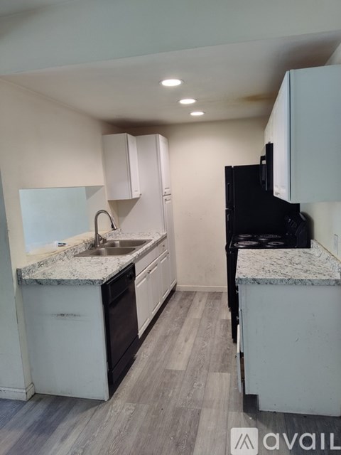 A kitchen with a black fridge and white cabinets.
