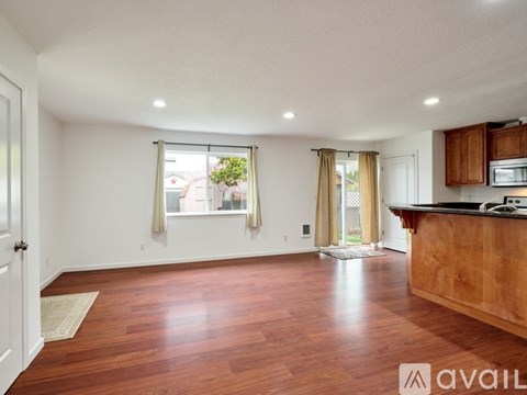 A spacious room with wooden floors and a kitchen area with a counter and cabinets.