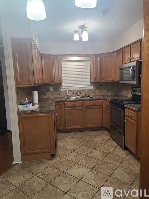 A kitchen with wooden cabinets and a tile floor.