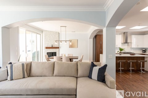A modern living room with a large beige sofa and a kitchen area in the background.