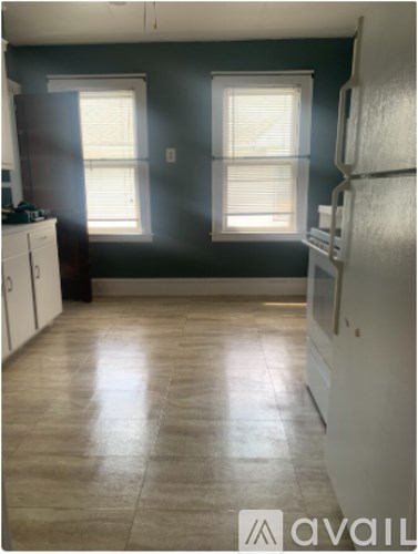 A kitchen with a refrigerator, cabinets, and a window.