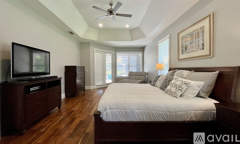 A bedroom with a large bed, a television, and a painting on the wall.