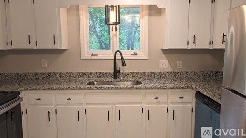 A kitchen with white cabinets and a granite countertop.