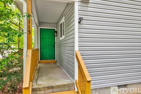A house with a green door and a wooden staircase leading to the entrance.