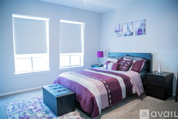 A bedroom with a large bed and a blue ottoman.