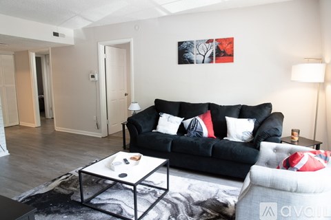 A black couch with red and white pillows sits in a living room.