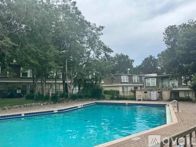 A swimming pool surrounded by trees and a house in the background.