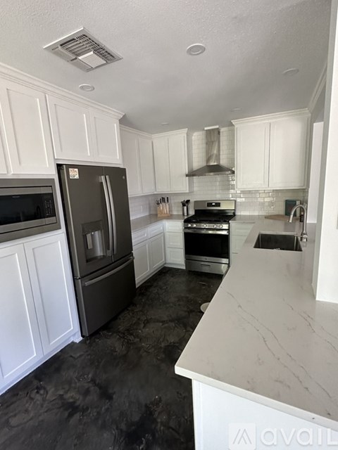 A kitchen with white cabinets and a marble counter.