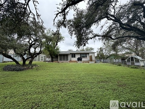 A house with a yard and trees in front of it.