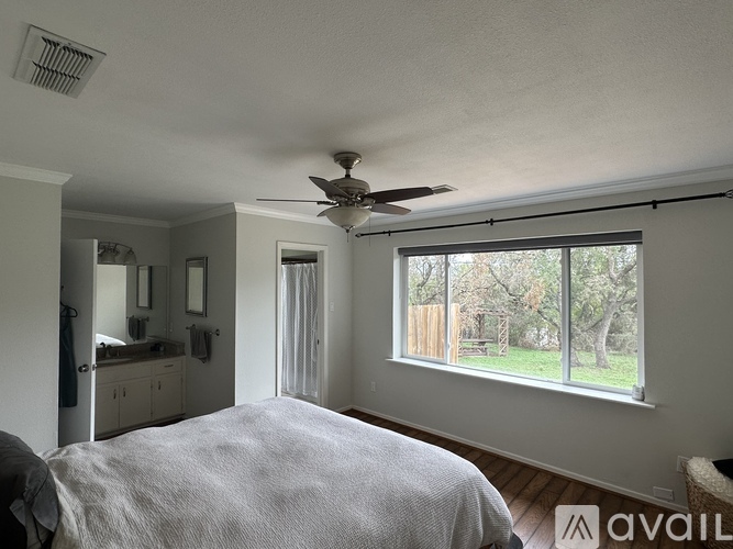 A bedroom with a large bed and a ceiling fan.